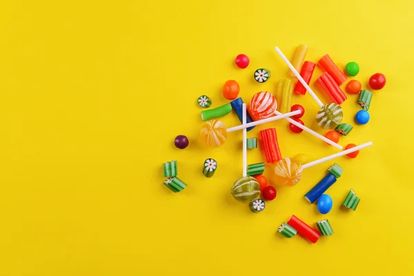 Colorful candies on yellow background — Stock Photo, Image