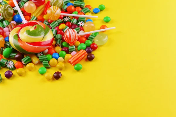 Colorful candies on yellow background — Stock Photo, Image