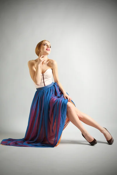 Expressive young model sitting on chair on gray background Stock Picture