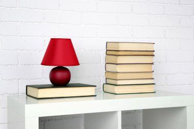 Kitap ve tuğla duvar arka lamba ile ahşap raf