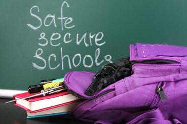 Blackboard arka plan üzerinde ahşap masa üzerinde okul sırt çantası silah