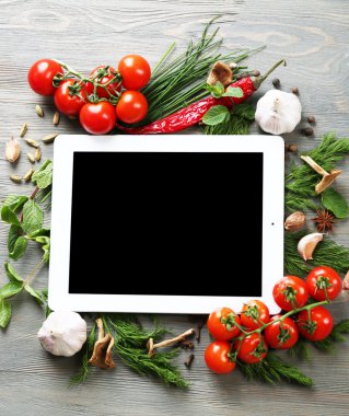 Taze otlar, domates ve baharat ahşap arka plan üzerinde dijital tablet
