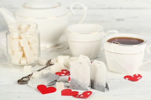 Coração em forma de etiquetas de teca, caixa e bule de chá no fundo de madeira — Fotografia de Stock