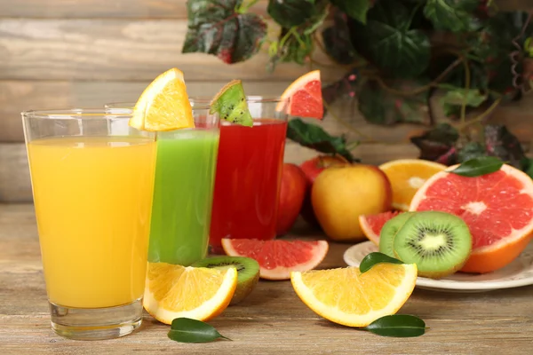 Fresh juices with fruits on wooden table — Stock Photo, Image