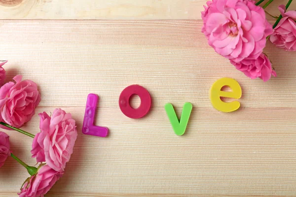 Ahşap arka plan üzerinde kelime aşk ile güzel güller