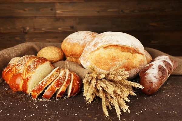 Different bread with ears on wooden background — Stock Photo, Image
