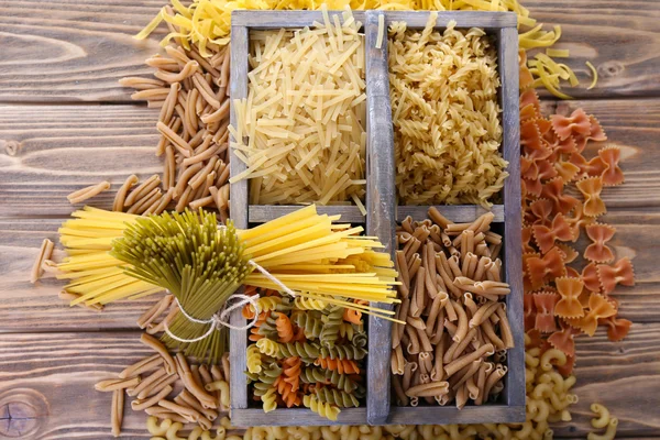 Diferentes tipos de pasta en caja sobre fondo de madera —  Fotos de Stock