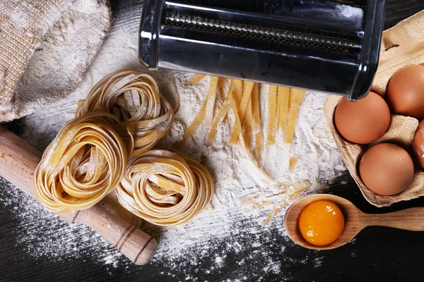 Máquina de hacer pasta de metal e ingredientes para pasta sobre fondo de madera — Foto de Stock