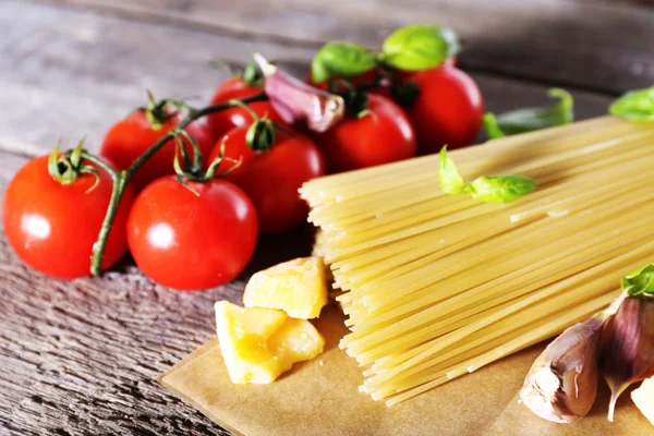 Pasta with cherry tomatoes and other ingredients on wooden table background — Stock Photo, Image