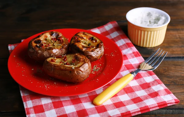 Batatas assadas em prato e molho na mesa de perto — Fotografia de Stock