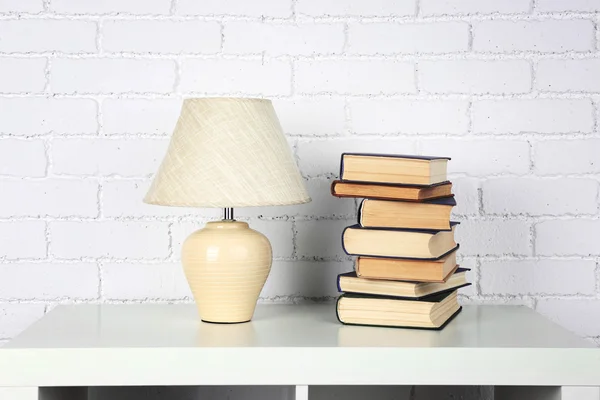 Kitap ve tuğla duvar arka lamba ile ahşap raf — Stok fotoğraf