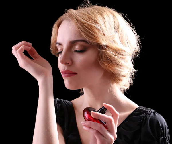 Beautiful young woman with perfume bottle on black background — Stock Photo, Image