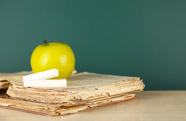 Livres anciens, pomme et craie sur fond de tableau noir — Photo