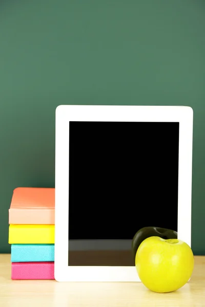 Tablet on table, on green blackboard background — Stock Photo, Image