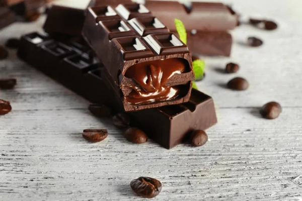 Plněná Čokoláda s kávová zrna na dřevěný stůl, detail — Stock fotografie