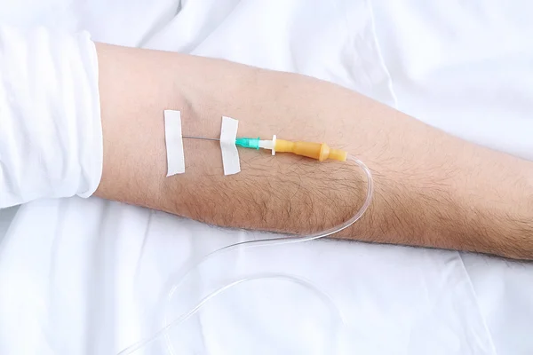 Man hand with dropper needle on bed close-up — Stock Photo, Image