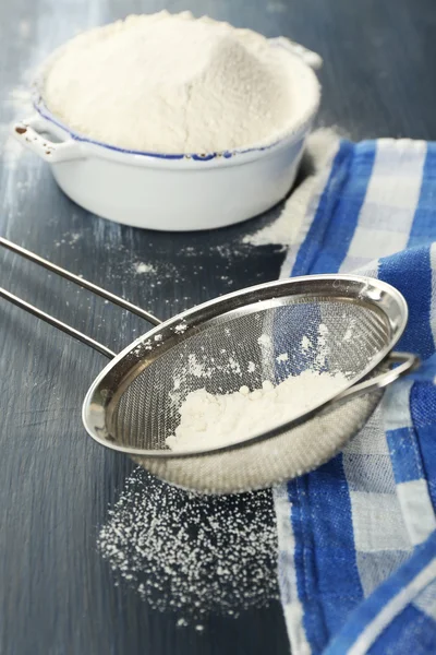 Sifting flour through sieve on wooden table, closeup — Stock Photo, Image