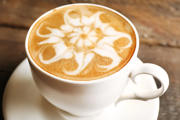 Taza de café con leche arte en la mesa de madera, primer plano — Foto de Stock