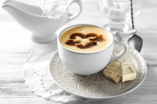 Xícara de café arte latte na mesa de madeira, no fundo claro — Fotografia de Stock