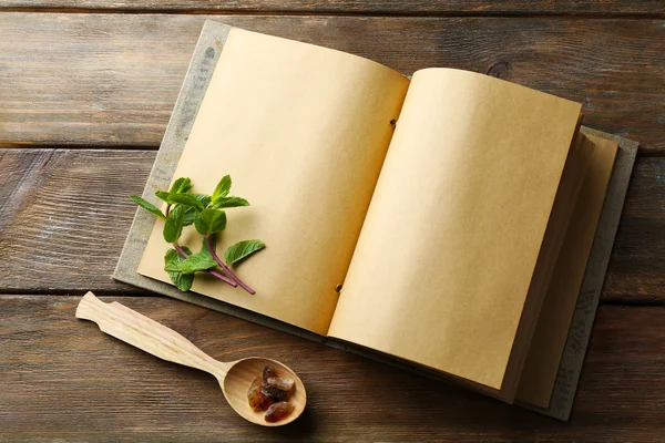 Open recipe book with mint leaves on wooden background — Stock Photo, Image