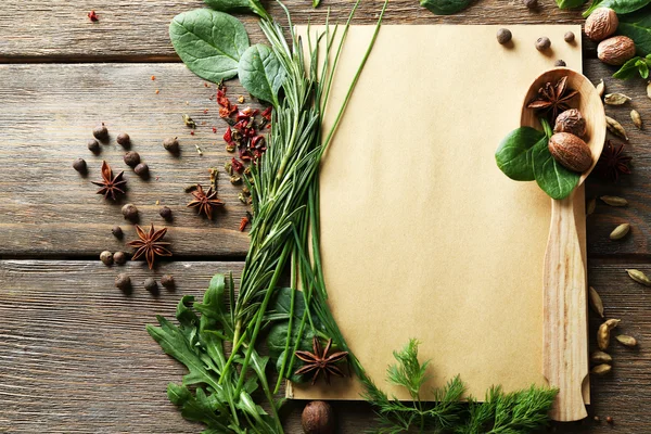 Livro de receitas aberto com ervas frescas e especiarias em fundo de madeira — Fotografia de Stock