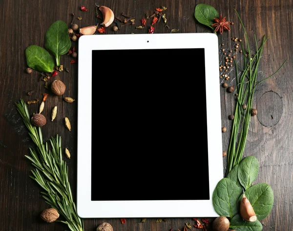 Digital tablet with fresh herbs and spices on wooden background — Stock Photo, Image