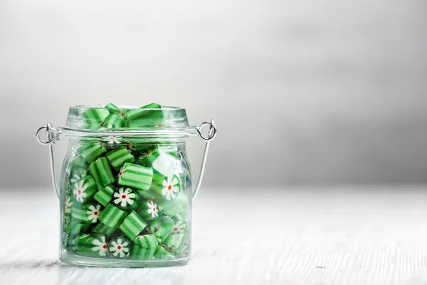 Bonbons colorés en pot sur la table sur fond en bois — Photo