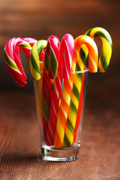 Kleurrijke snoep stokken in glas op tafel op houten achtergrond — Stockfoto