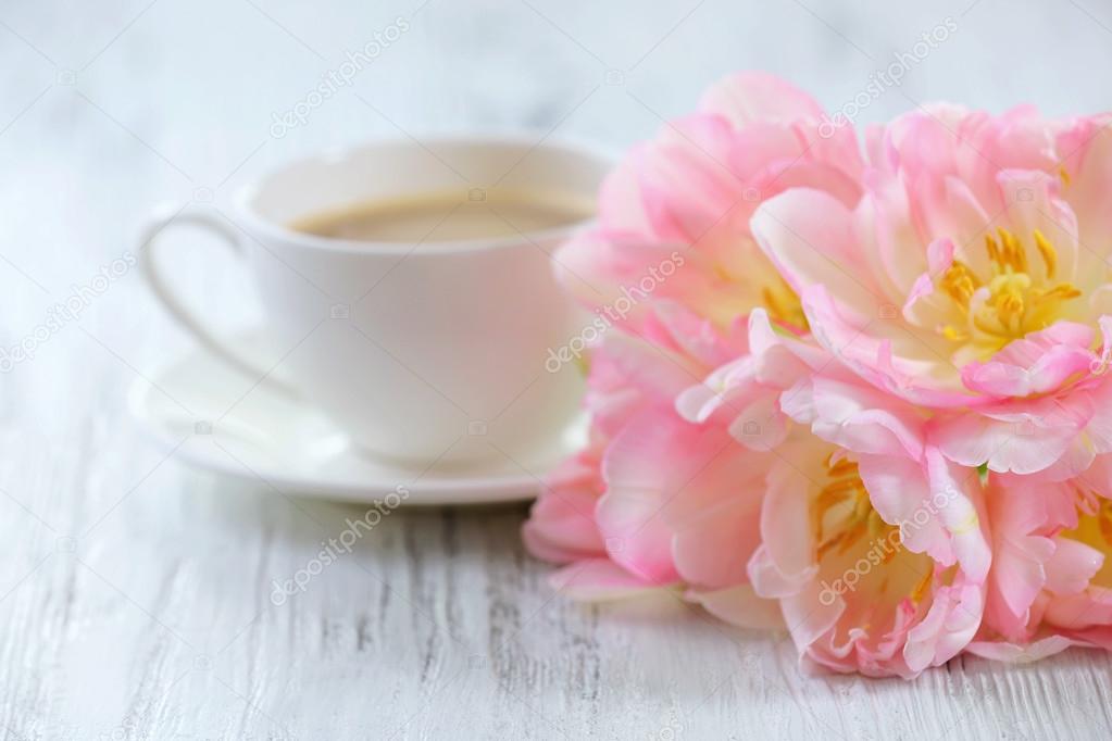 Pink tulips with cup of coffee on wooden background