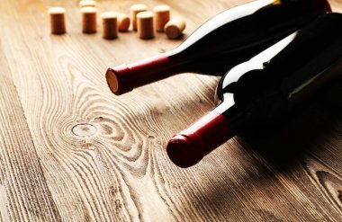 Ahşap masa arkasında mantarlı cam şarap şişesi.