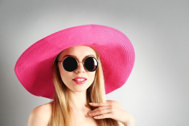 Pembe şapka ile güneş gözlüğü gri arka plan üzerinde etkileyici genç modeli