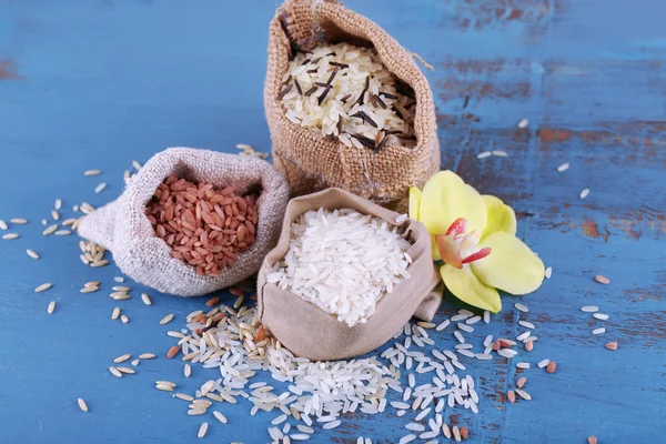 Diferentes tipos de arroz en sacos sobre fondo de madera — Foto de Stock