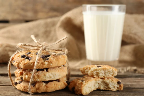 Gustosi biscotti e bicchiere di latte su fondo rustico in legno — Foto Stock