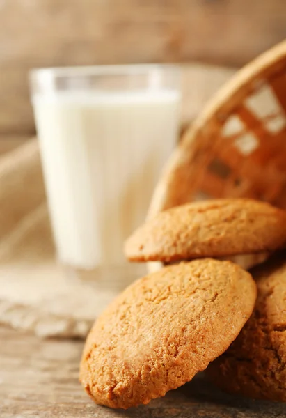 Sabrosas galletas y vaso de leche sobre fondo rústico de madera — Foto de Stock