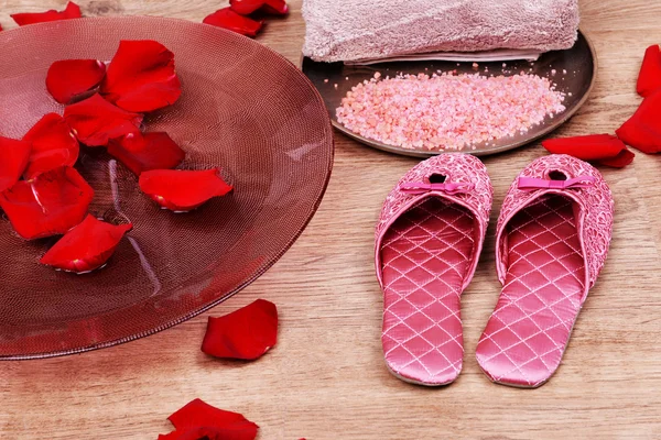 Spa bowl with water, rose petals, towel and slippers on light background. Concept of pedicure or natural spa treatment — Stock Photo, Image