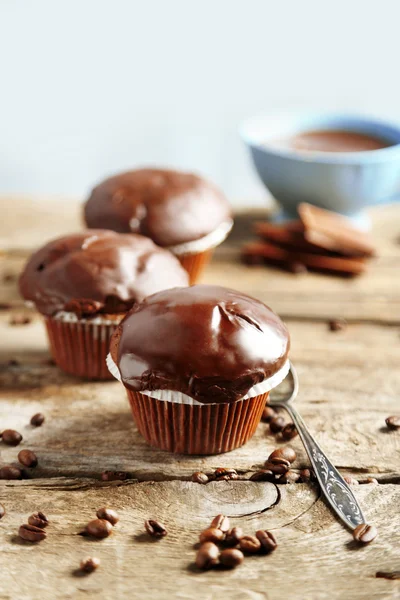 Gustosi muffin al cioccolato fatti in casa e una tazza di caffè su un tavolo di legno, su sfondo chiaro — Foto Stock