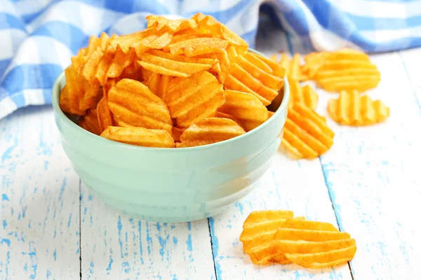 Delicious potato chips in bowl on wooden table close-up — Stock Photo, Image