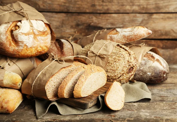 Verschillende vers brood, op oude houten tafel — Stockfoto