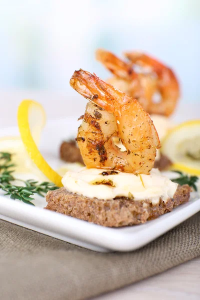 Vorspeise Canape mit Garnelen und Zitrone auf dem Tisch auf hellem Hintergrund — Stockfoto