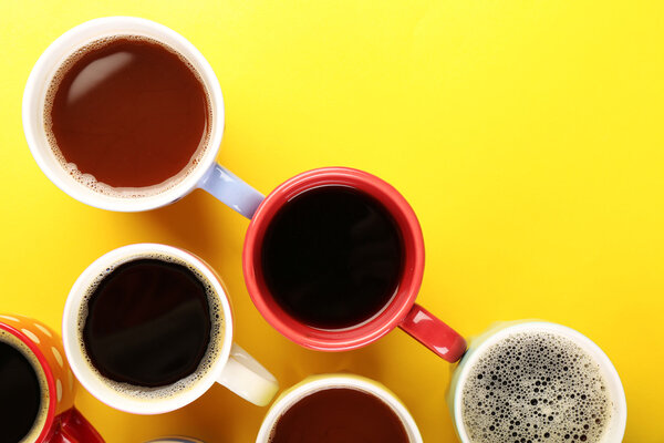 Many cups of coffee on color table, top view