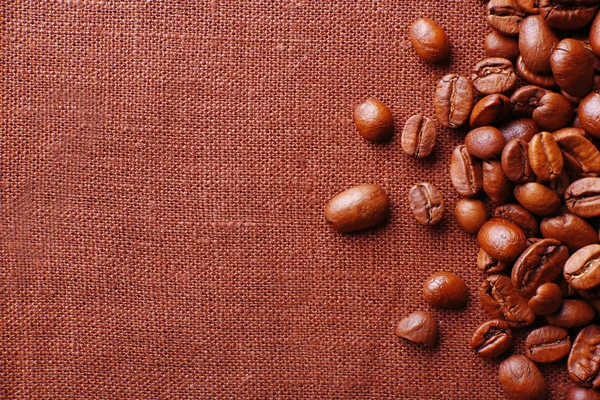 Frame of coffee beans on color sackcloth background — Stock Photo, Image