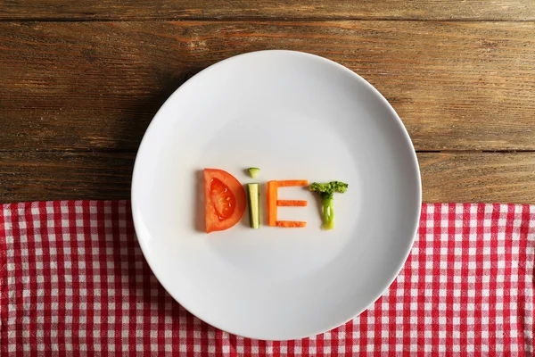 Word dieet gemaakt van gesneden groenten in witte plaat met servet op houten achtergrond — Stockfoto