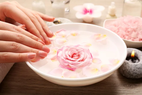 Kvinnliga händer och skål med spa vatten med blommor, närbild — Stockfoto