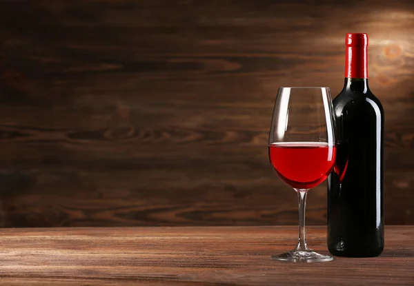 Wineglass and bottle on wooden background — Stock Photo, Image