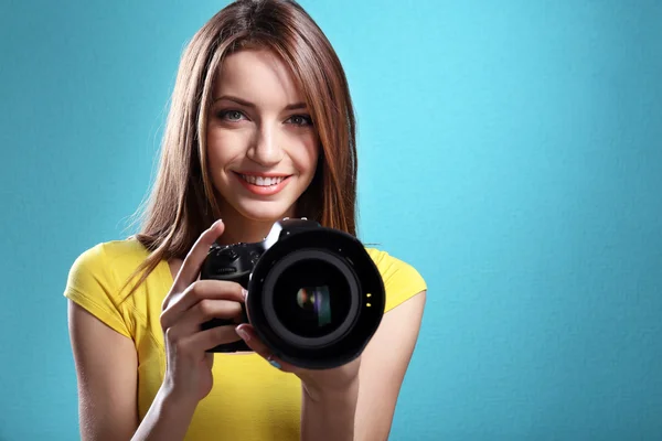 Joven fotógrafa tomando fotos sobre fondo azul —  Fotos de Stock