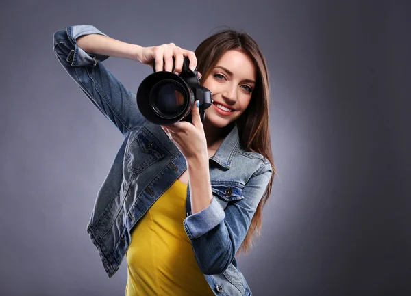 Junge Fotografin fotografiert auf grauem Hintergrund — Stockfoto