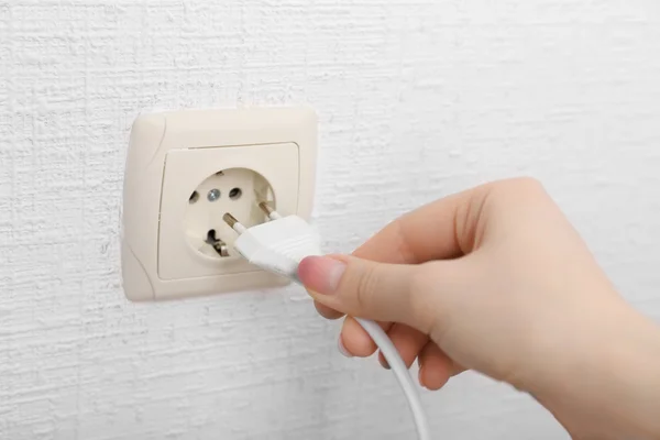 Mão colocando plug-in tomada de eletricidade de perto — Fotografia de Stock