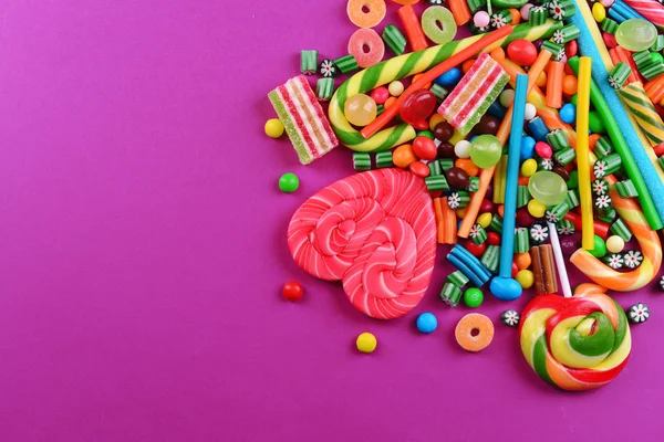 Красочные конфеты на фиолетовом фоне — стоковое фото