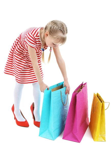 Hermosa niña en los zapatos de mamá con bolsas de compras aisladas en blanco — Foto de Stock