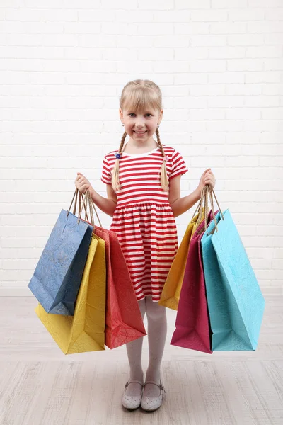 Hermosa niña con bolsas de compras en la habitación — Foto de Stock